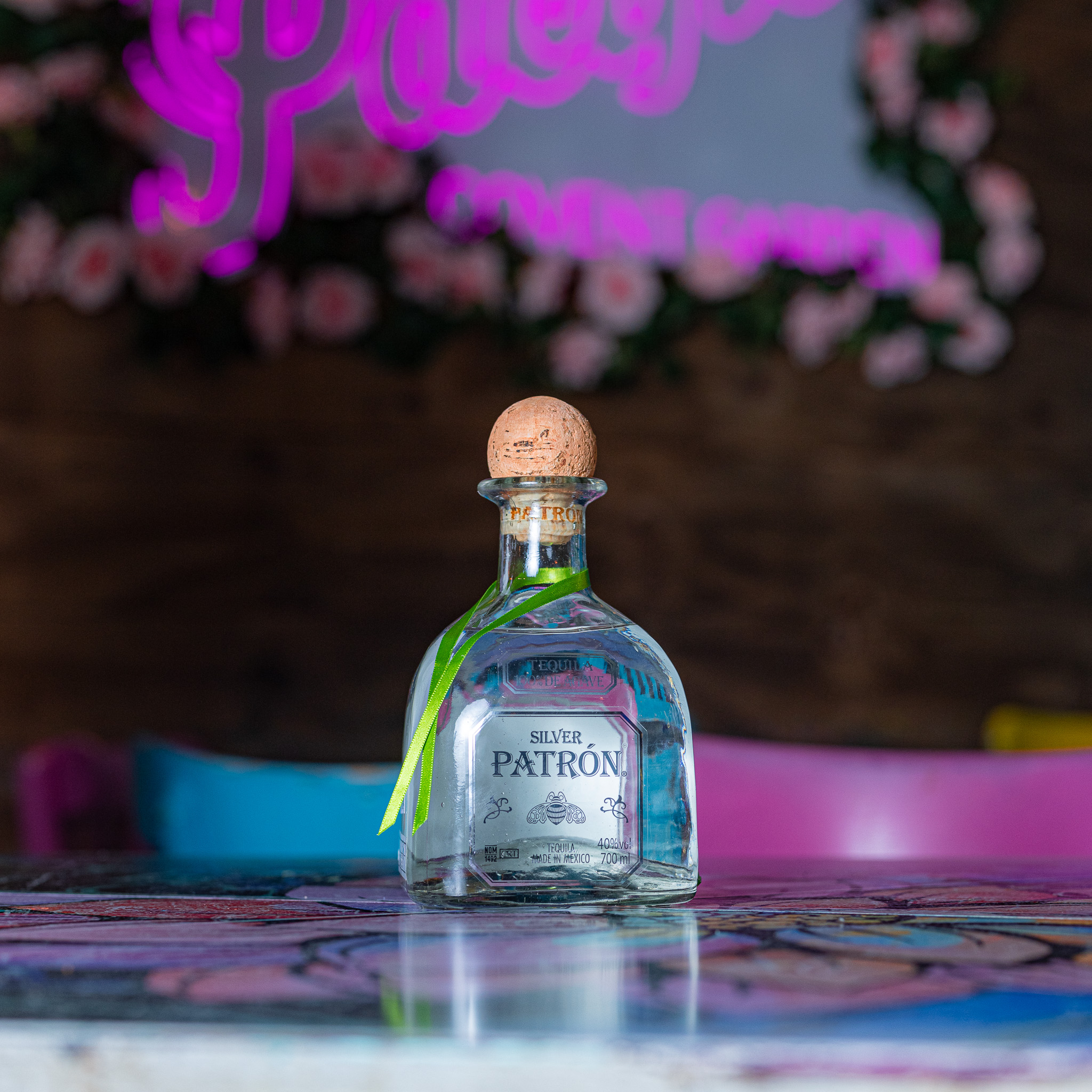 A bottle of Patron Silver tequila displayed at a lively Warsaw nightclub with neon lights in the background. Perfect for a premium tequila experience in the city's top nightlife venues.