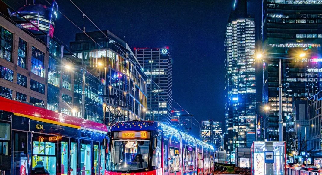 Tram in the heart of Warsaw at night, showcasing the city's vibrant nightlife transportation options with glowing lights and towering skyscrapers.