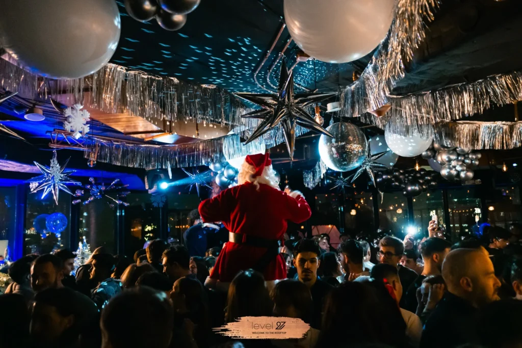 Santa Claus dancing above a packed crowd during a festive rooftop club night in Warsaw, vibrant lights and disco decorations, Warsaw party calendar