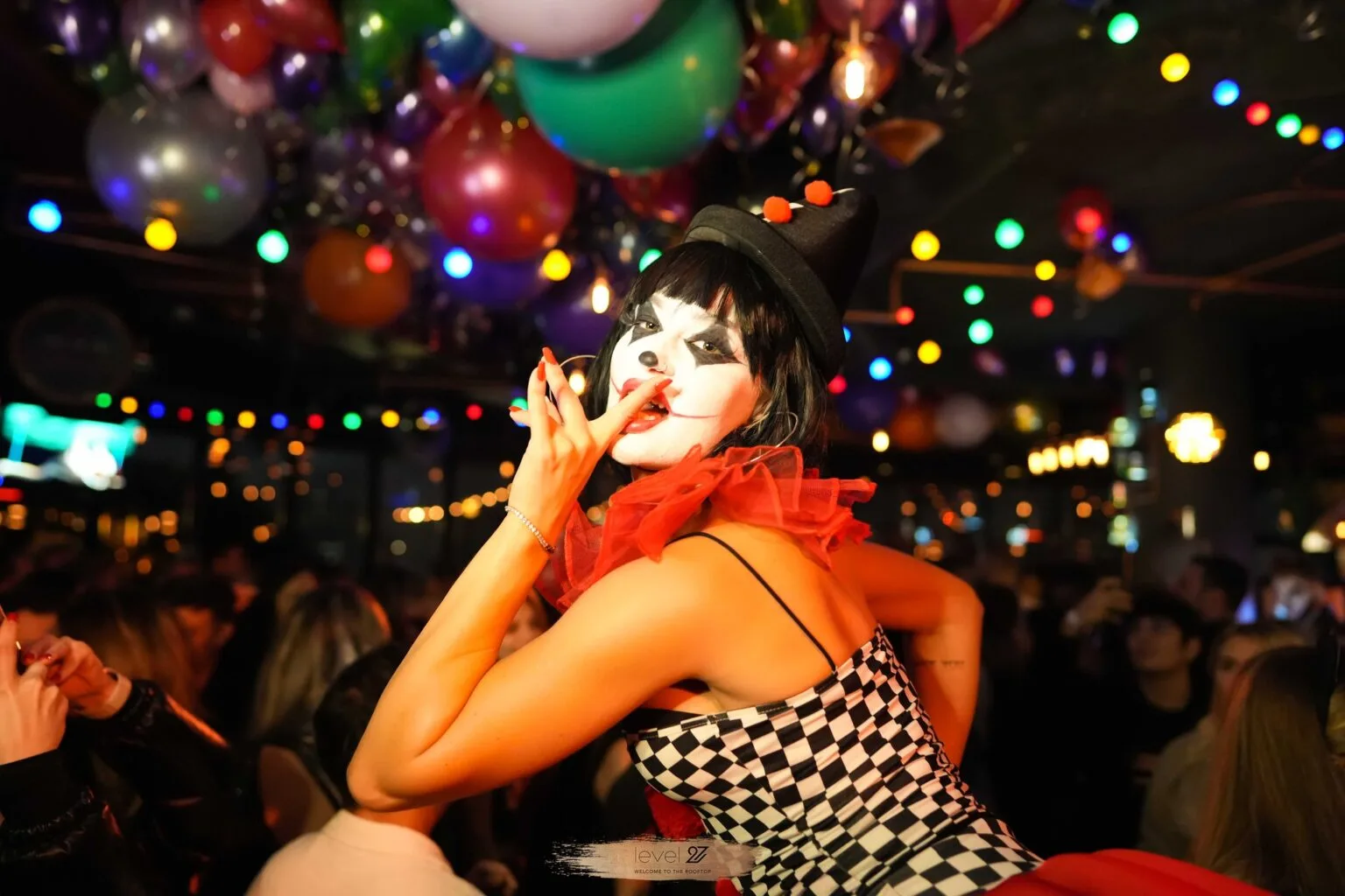 Halloween party performer with mime-style makeup and colorful balloons during a crowded club night in Warsaw, vibrant nightlife atmosphere, Warsaw party calendar